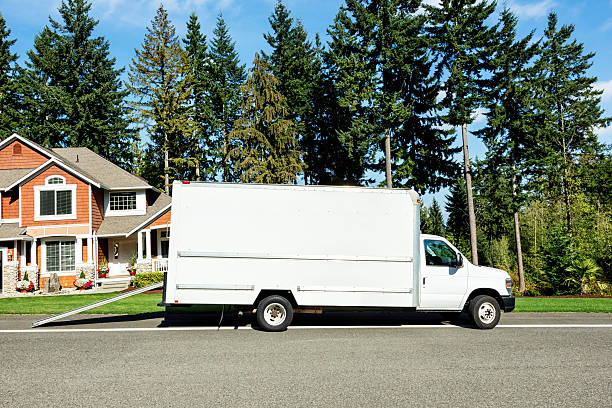 Photo of a plain white moving truck parked on the street in front of a house.