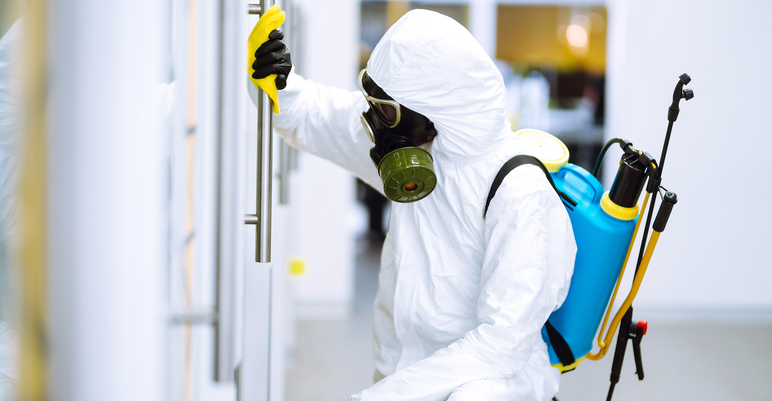 person-wearing-hazmat-suit-disinfecting-a-door